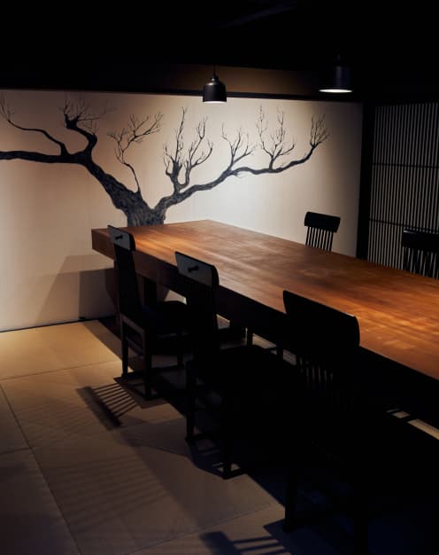落ち着いた照明と重厚感ある木製の長テーブルが置かれたお食事スペース